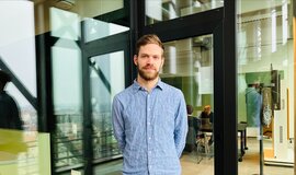 Christian Pfeiffer, Projektmanager Perception bei der Digitalen Schiene Deutschland, steht vor einer gläsernen Wand. | © Digitale Schiene Deutschland, DB InfraGO AG
