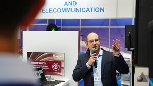 Ein Mann hält einen Vortrag an einem Messestand.