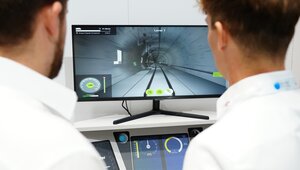 Zwei Menschen stehen vor einem Bildschirm auf einem Holztisch. Der Bildschirm zeigt eine Simulation der Technik ATO GoA2