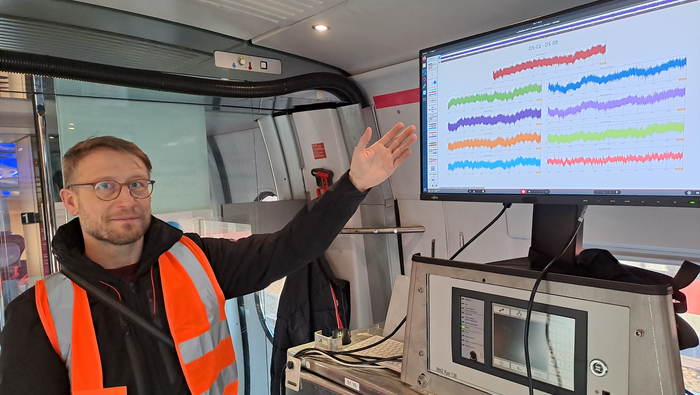 Martin Köppel in a high-visibility vest points to a screen with different colored lines.