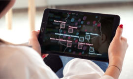 Eine Frau hält ein Tablet mit einer Deutschlandkarte, auf der diverse bunte Hashtags und Markierungen zu erkennen sind.