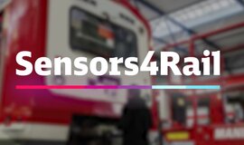 Red Train in maintenance depot. The words “Sensors4Rail” are emblazoned in the foreground of the picture Red Train in maintenance depot. The words “Sensors4Rail” are emblazoned in the foreground of the picture