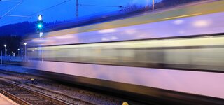 A fast-passing white train at dusk. A fast-passing white train at dusk.