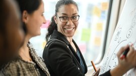3 people talking to each other in front of a flipchart. 3 people talking to each other in front of a flipchart.