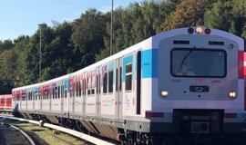 Foto zeigt den fahrenden Laborzug Sensors4Rail, der in den Farben der Digitalen Schiene Deutschland beklebt ist vor einigen grünen Bäumen. Foto zeigt den fahrenden Laborzug Sensors4Rail, der in den Farben der Digitalen Schiene Deutschland beklebt ist vor einigen grünen Bäumen.