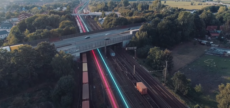 Straßenüberführung führt über mehrgleisige Bahnstrecke, auf der Züge fahren.