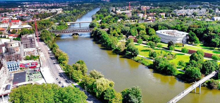 Luftbild von Ingolstadt: Links befindet sich eine zweispurige Autostraße. Rechts davon und mittig im Bild fließt ein Fluss. Über den Fluss führt eine Eisenbahnbrücke. Luftbild von Ingolstadt: Links befindet sich eine zweispurige Autostraße. Rechts davon und mittig im Bild fließt ein Fluss. Über den Fluss führt eine Eisenbahnbrücke.