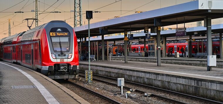 Ein roter Zug steht an einem Bahnhof am Bahnsteig. Auf seiner Anzeige steht Augsburg HBF Ein roter Zug steht an einem Bahnhof am Bahnsteig. Auf seiner Anzeige steht Augsburg HBF