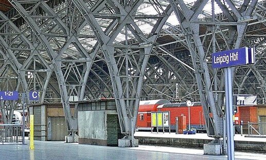 Trainstation with steelconstruction. Red Train standing at platform. Sign at platforms says "Leipzig HBF" Trainstation with steelconstruction. Red Train standing at platform. Sign at platforms says "Leipzig HBF"