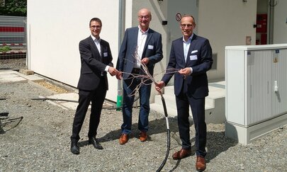 Das Bild zeigt Andre Rodenbeck (CEO Rail Infrastructure bei Siemens Mobility), Uwe Kober (Bürgermeister der Stadt Altena) und Jens Bergmann (Vorstand Finanzen und Controlling bei DB InfraGO AG) vor dem neuen Stellwerks-Modul in Altena.