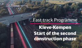 Road bridge leads over multi-track railroad line. In the foreground of the picture is written: Fast-track Programme, Kleve-Kempen Start of the second construction phase Road bridge leads over multi-track railroad line. In the foreground of the picture is written: Fast-track Programme, Kleve-Kempen Start of the second construction phase