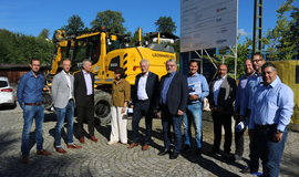Der Bundestagsabgeordnete Alois Rainer (5. v. l.) und die Bürgermeisterin der Stadt Zwiesel Elisabeth Pfeffer (4. v. l.) gemeinsam mit Vertretern der DB Netz AG und der PINTSCH GmbH in Zwiesel (Quelle: DB Netz AG/Manfred Gollmann). Alle stehen vor einem Baustellenschild und einem gelben Bagger. Der Bundestagsabgeordnete Alois Rainer (5. v. l.) und die Bürgermeisterin der Stadt Zwiesel Elisabeth Pfeffer (4. v. l.) gemeinsam mit Vertretern der DB Netz AG und der PINTSCH GmbH in Zwiesel (Quelle: DB Netz AG/Manfred Gollmann). Alle stehen vor einem Baustellenschild und einem gelben Bagger.