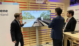 Drei Personen stehen vor einem Bildschirm, auf welchem eine Simulation des Digitalen Zwilings gezeigt wird.