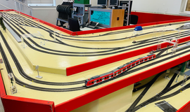 Eisenbahnbetriebsfeld Darmstadt - Unverzichtbare Simulationsplattform: Zu sehen ist eine Modelleisenbahn mit mehreren Gleisen und einem roten Modellzug. Eisenbahnbetriebsfeld Darmstadt - Unverzichtbare Simulationsplattform: Zu sehen ist eine Modelleisenbahn mit mehreren Gleisen und einem roten Modellzug.