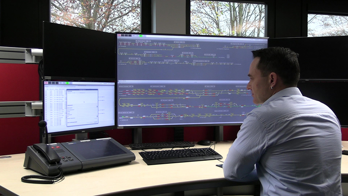 A person sitting in front of a screen with the integrated control and operating system on screen.